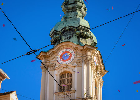 Part of the clock tower of the Parish Church of the Holy Blood in Graz, Austria against a blue skyの写真素材