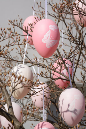 Light pink Easter decorative egg among branches, selective focus, vertical format
