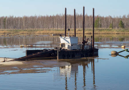 A sewage barge cleans the lake against the background of the forest.の写真素材