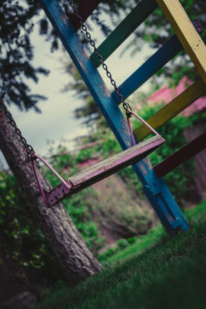 wooden swing on chains in the garden on a background of greeneryの写真素材