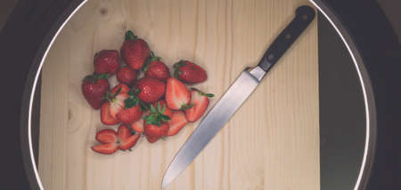 cut strawberries and knife on a cutting board with blurの写真素材