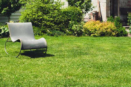 Chair country on a lawn against a green bush