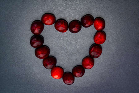 Heart made of cherries on a dark backgroundの写真素材