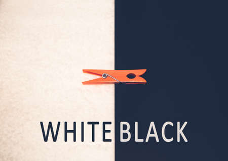 An orange clothespin on a black and white background with the words "WHITE BLACK"の写真素材