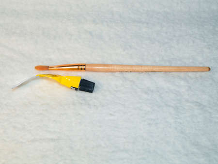Paint brush and tube of yellow paint on a white backgroundの写真素材