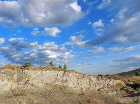 Clouds in clear weather against a small hillock in summerの写真素材