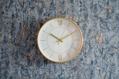 Gold clock on the wall on a homogeneous background