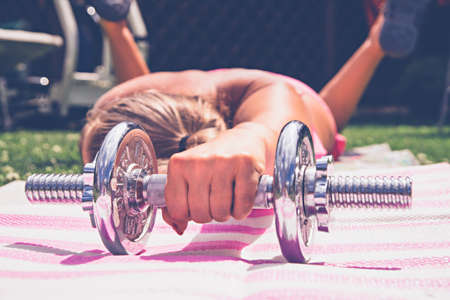 Girl goes in for sports with dumbbells in nature