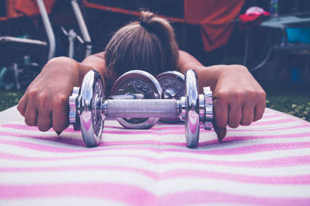 Girl goes in for sports with dumbbells in natureの写真素材