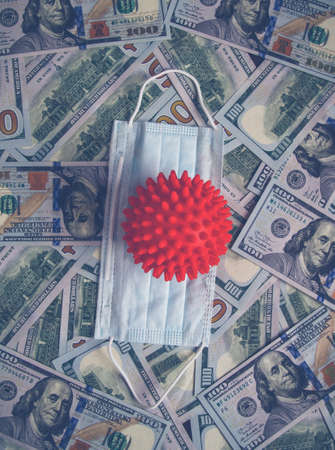 White mask from coronavirus on banknotes. White Covid mask lies on banknotes. Red ball of coronavirus on banknotesの写真素材