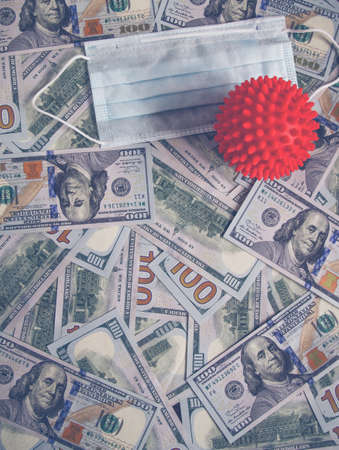 White mask from coronavirus on banknotes. White Covid mask lies on banknotes. Red ball of coronavirus on banknotesの写真素材