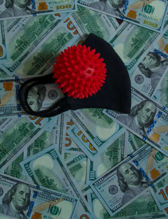 Black mask from coronavirus on banknotes. Black Covid mask lies on banknotes. Red ball of coronavirus on banknotesの写真素材