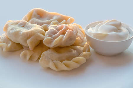 Dumplings with sour cream on a white plate close upの写真素材