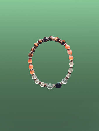 Bracelet from beads of different stones on a green backgroundの写真素材