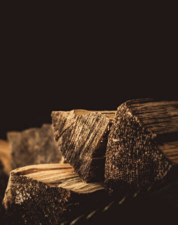 Chipped firewood lie near the fireplace on a dark backgroundの写真素材