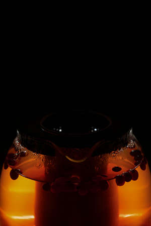 hot tea with berries in a glass teapot, on a dark backgroundの写真素材