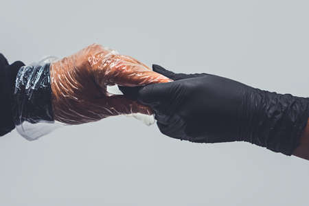 Two hands in sterile gloves reach out to each other. Skin protection during epidemics and quarantine.の写真素材