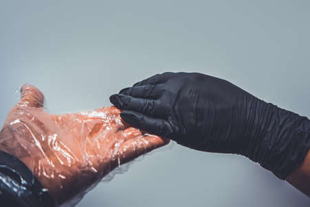 Two hands in sterile gloves reach out to each other. Skin protection during epidemics and...