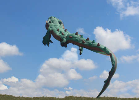 TRYHUTTY INTERNATIONAL KITE FESTIVAL, UKRAINE - MAY 22, 2017: Big green kite is in the blue sky with small clouds.Flying crocodile .Kite festival. Family holiday. Kite competitionのeditorial素材