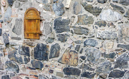 Small rusty doors on a stone wall of an old building. Doors are located high above the ground. Large...