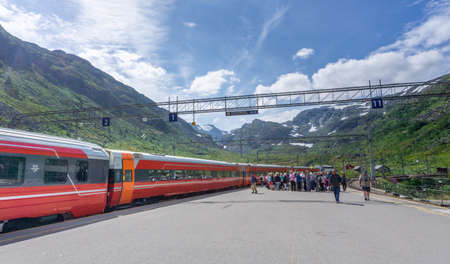 MYRDAL STATION,Norway- JULY 21 2018: long red train on a background of picturesque green hills....