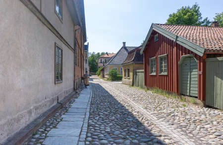 OSLO, NORWAY - July 19, 2018: Street in the Old City section of the museum. A girl in a traditional outfit with a basket is walking along the street.Reconstruction of everyday features of Norwegian cities.のeditorial素材