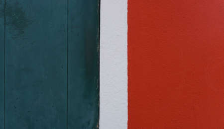 A fragment of a wooden door and a concrete wall, painted in dark blue, white and red. The vertical colored stripes are similar to the Italian flag. Large free space.の写真素材