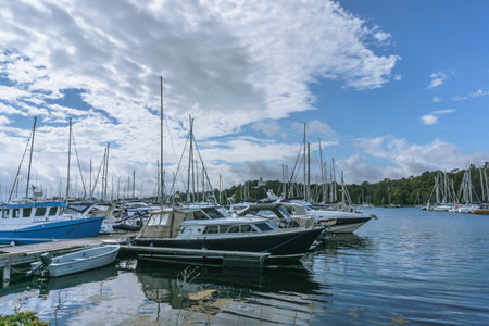 Under the blue sky stands a large number of sea yachts without sails. Yacht parking in the harbor, yacht club in Oslo, Norway. Beautiful yachts against the background of Norwegian fjordsの写真素材