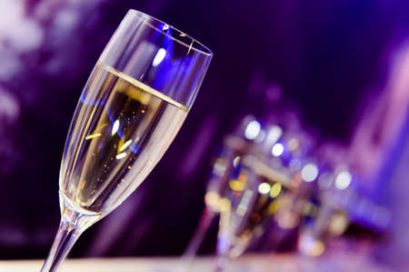 Luxury party champagne glass in nightclub neon lilac, blue and purple lights, blurry closeup