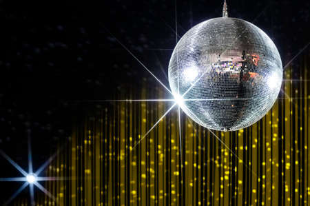 Disco ball with stars in nightclub with striped yellow and black walls lit by spotlight, party and nightlife entertainment industryの写真素材