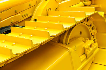 Bulldozer tracks and drive gear with sprocket mechanism, large construction machine with bolts and yellow paint coating, heavy industry, detailの写真素材