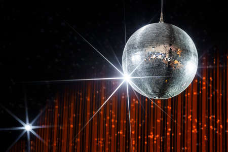 Disco ball with stars in nightclub with striped orange and black walls lit by spotlight, party and nightlife entertainment industryの写真素材
