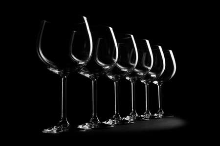 Wine glasses standing in row, empty glasswares with light pattern isolated on black background, selective focusの写真素材