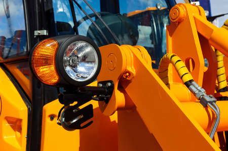 Bulldozer headlight, huge orange powerful construction machine with light equipment also used for...