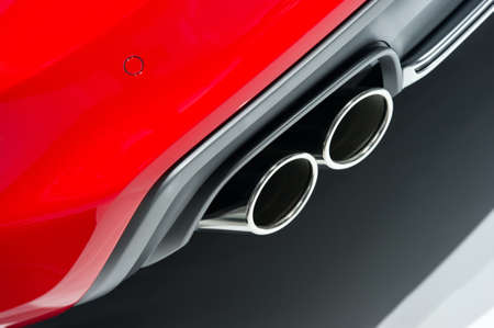 Chrome exhaust pipes of powerful sport car with red bodywork and grey bumperの写真素材