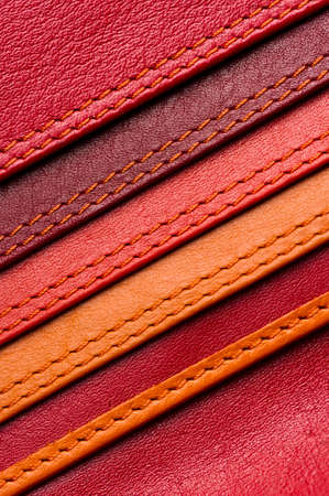 Leather samples with stitches, natural materials with seams of red, maroon, brown, orange colors and other warm shades, women bag detail, macro shot, selective focusの写真素材
