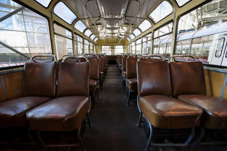 Retro bus inside, old public transport interior with leather seats in row, chrome handles for passengers and big windows, vintage vehicle, nostalgia backgroundの写真素材