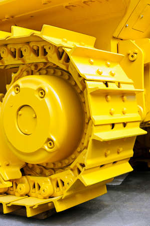 Bulldozer tracks and drive gear with sprocket mechanism, large construction machine with bolts and yellow paint coating, heavy industry, detailの写真素材
