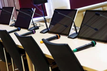 Conference room with microphones and displays on table and chairs for participants in row, business concept, before meeting, selective focusの写真素材