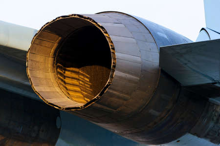 Fighter jet engine exhaust, military aircraft rear view, plane nozzle with part of wing and fuselage lit by evening sun, supersonic air force, modern aviation and aerospace industryの写真素材