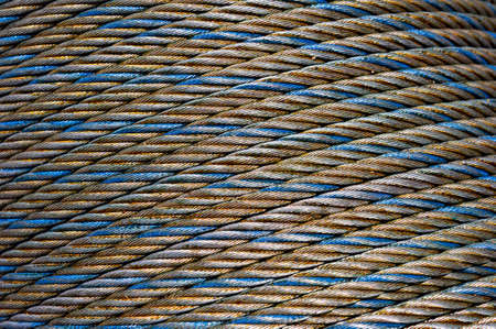 Steel cable coil, iron rope, wire of gray, blue and gold colors, hawser abstract texture, industrial backgroundの写真素材