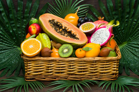 Fresh Thai fruits in wicker basket on palm leaves and wooden background, healthy food, diet...