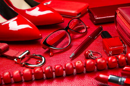 Red woman accessories, jewelry, cosmetic, shoes and other luxury objects on a leather background,...