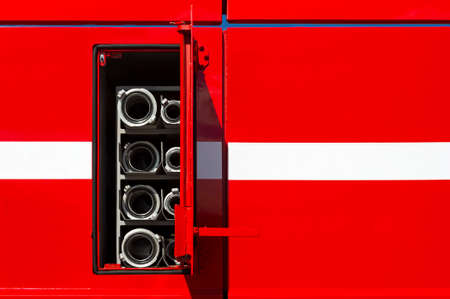 Firefighter car body with fire hoses and pump in compartment with open door, red bodywork with white...