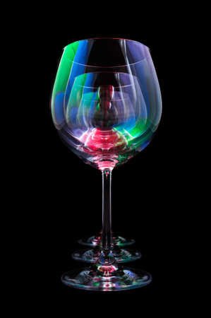 Party wine glasses lit by red, green, blue nightclub lights, nightlife and entertainment industry, objects in row isolated on black backgroundの写真素材