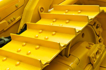Bulldozer tracks and drive gear with sprocket mechanism, large construction machine with bolts and yellow paint coating, heavy industry, detailの写真素材