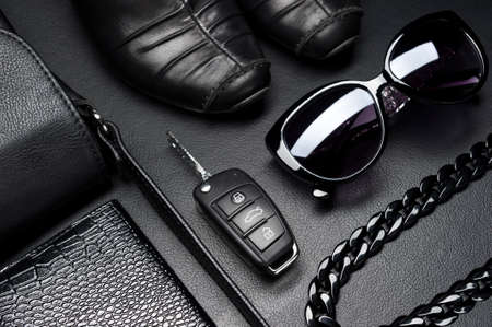 Woman accessories in business style, shoes, car key, jewelry and other luxury objects for businesswoman on leather black background, fashion industry, selective focusの写真素材