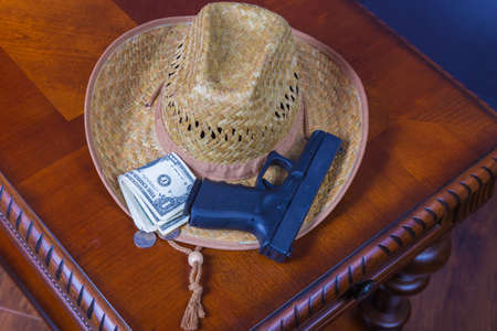 Hat, handgun and money on wooden deskの写真素材