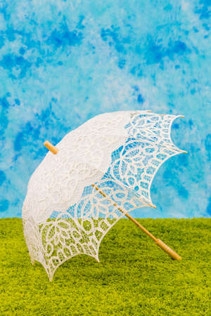 White lacy umbrella on sky and grass backroundの写真素材