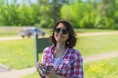 Girl with smartphone in pink shirt on the green nature backgroundの写真素材